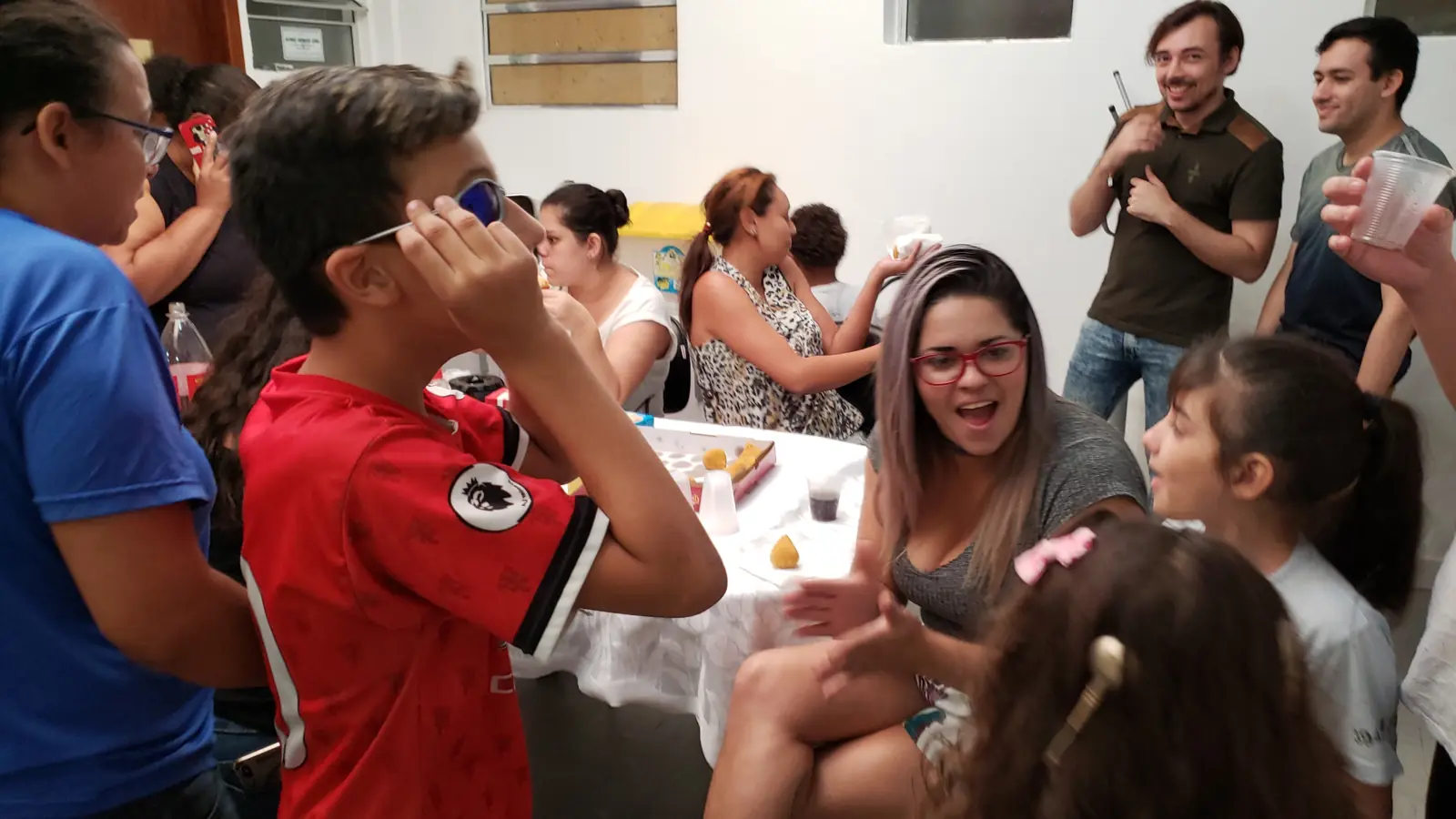 Crianças, famílias e educadores conversando em Libras durante uma festa na AADAS